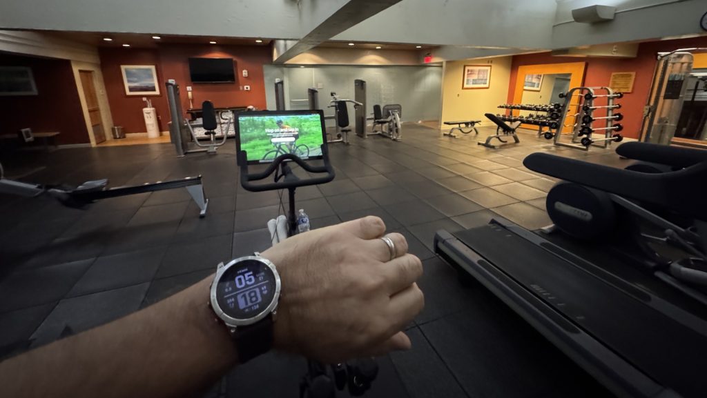 a person's hand with a watch on a black surface in a gym